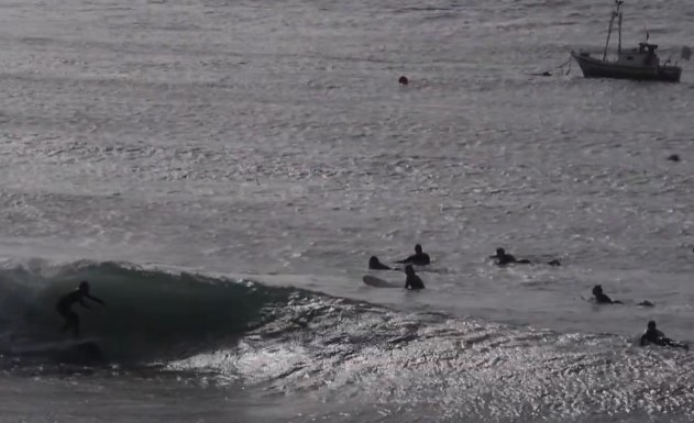surfistas en Almería con un barco de fondo