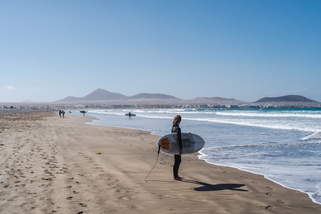 chica surfista en una playa de Lanzarote con su tabla